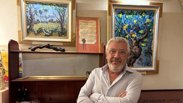 Mathieu Laurent devant les tableaux de son père, exposés au Cheval Blanc